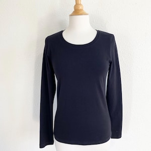 May include: A black long-sleeved shirt with a round neckline. The shirt is on a white mannequin.