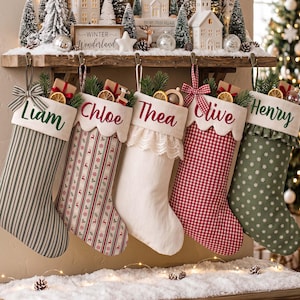 May include: Five personalized Christmas stockings hanging from a wooden shelf. The stockings feature names Liam, Chloe, Thea, Olive, and Henry in script font. They are decorated with various patterns including stripes, reindeer, lace, gingham, and snowflakes.