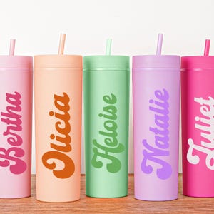 May include: Five colorful tumblers with lids and straws, each in a different pastel shade: pink, peach, green, lavender, and hot pink. Each tumbler has a name printed on it in a retro font: Bertha, Olicia, Heloise, Natalie, and Juliet.