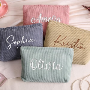May include: Five corduroy cosmetic bags in various colors: pink, blue, yellow, and green. Each bag has a name embroidered on it: Amelia, Sophia, Kristin, and Olivia. The bags are rectangular and have a ribbed texture.
