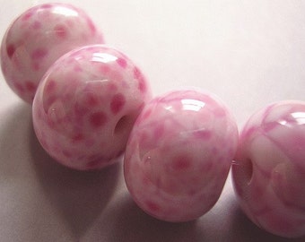 May include: A string of pink and white glass beads with a speckled pattern. The beads are round and have a glossy finish.