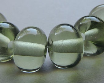 May include: A strand of six green glass beads with a white swirl inside each bead.