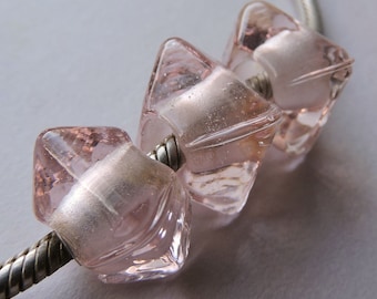 May include: Three pink glass beads with a starburst design, strung on a silver chain.