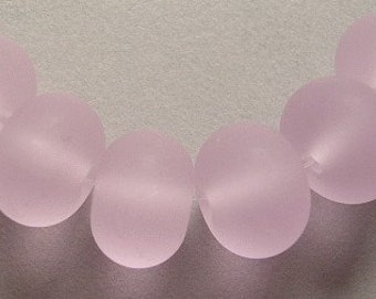 May include: A strand of seven frosted pink glass beads, strung on a clear thread.