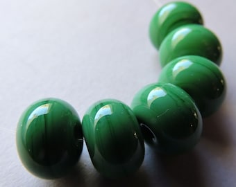 May include: A strand of six green glass beads with a marbled effect. The beads are round and have a glossy finish.