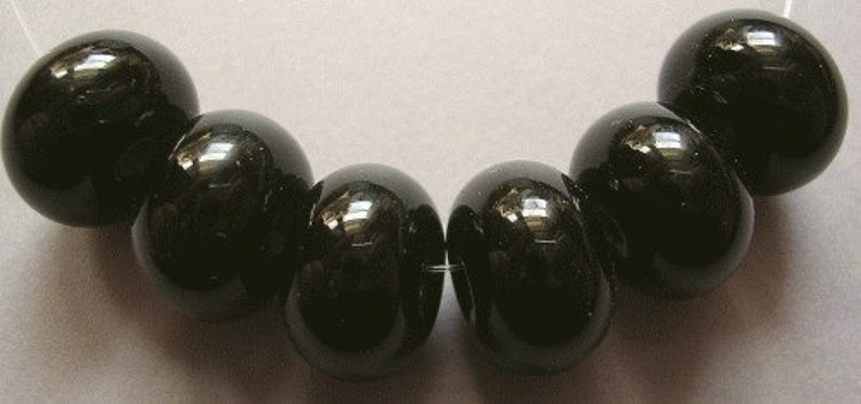 May include: A strand of seven black round beads, each with a smooth, glossy finish.