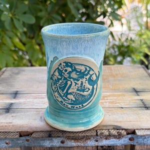 May include: A set of three ceramic mugs with a speckled, matte finish. The mugs are in shades of cream, light gray, and dark gray. Each mug has a simple, minimalist design, perfect for coffee or tea.