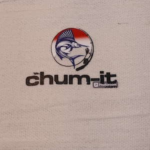以下が含まれることがあります： 白い布地に、黒と白のロゴ「chum-it」と、赤い、白い、青いマルリンの魚のロゴが円形に描かれている。