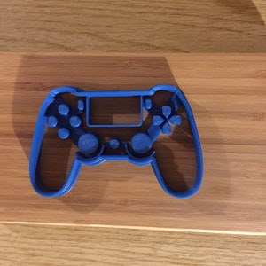 May include: A blue plastic cookie cutter shaped like a video game controller.