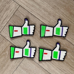 May include: Four iron-on patches featuring a green and white cartoon hand giving a thumbs up. The thumb is green and the hand is white with a purple stripe. The patches are approximately 5 cm wide.