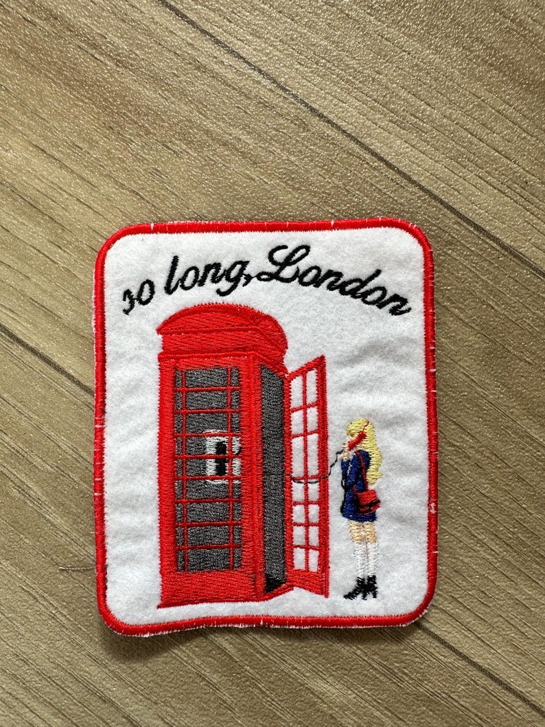 May include: Embroidered patch featuring a red London telephone booth with an open door and a person on the phone. The patch has the words "so long, London" in cursive script.