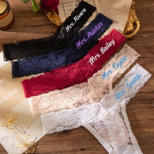 Könnte beinhalten: Fünf Spitzen-Tanga-Unterhosen in Schwarz, Marineblau, Rot, Creme und Weiß. Jeder Tanga ist mit einem Namen in einer Kontrastfarbe personalisiert. Die Namen sind Mrs. Rivera, Mrs. Austin, Mrs. Bailey, Mrs. Taylor und Mrs. Smith.