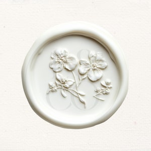 May include: White wax seal with a raised design of three white flowers and leaves.