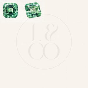May include: Two emerald green square-shaped gemstones with a faceted cut.