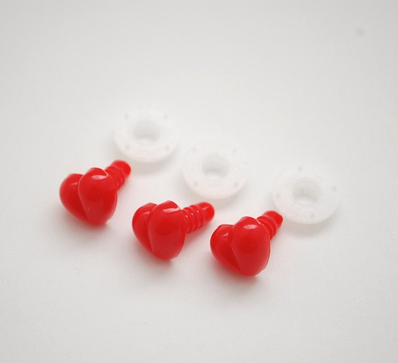 May include: Three red plastic safety eyes with a heart-shaped design, along with three white plastic washers. These craft supplies are used for making stuffed animals and other handmade projects.