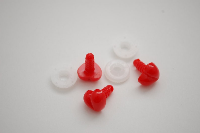 May include: Close-up of red plastic safety eyes with screw posts and white plastic washers. These craft supplies are used for making stuffed animals, dolls, and other handmade projects. The eyes are a bright, solid red color.