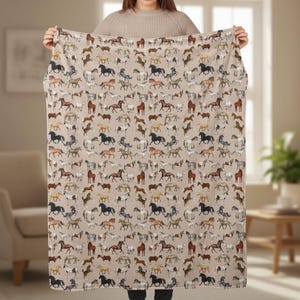 Woman holding beige horse plush blanket wide, full horse pattern throw, velveteen plush blanket size display, equestrian home decor, horse lover gift blanket, cozy western throw, farmhouse neutral bedding, horse girl present, soft warm winter blanket, country decor accessory, aesthetic horse pattern, plush bed throw, equestrian lifestyle decor, comfort gift idea, western bedroom blanket