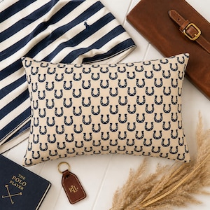 Preppy equestrian decor flat lay with horseshoe lumbar pillow, striped fabric and leather accessories, western home decor style