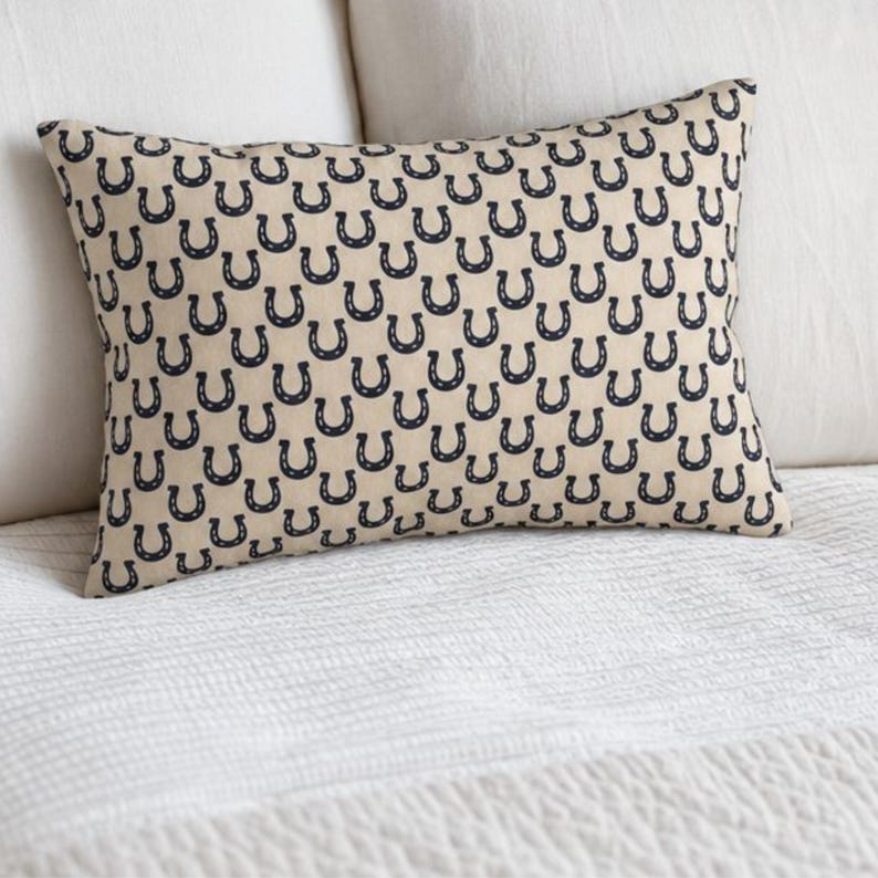 Horseshoe lumbar pillow cover on white bed, navy beige throw pillow, preppy equestrian decor for bedroom, horse pillow accent