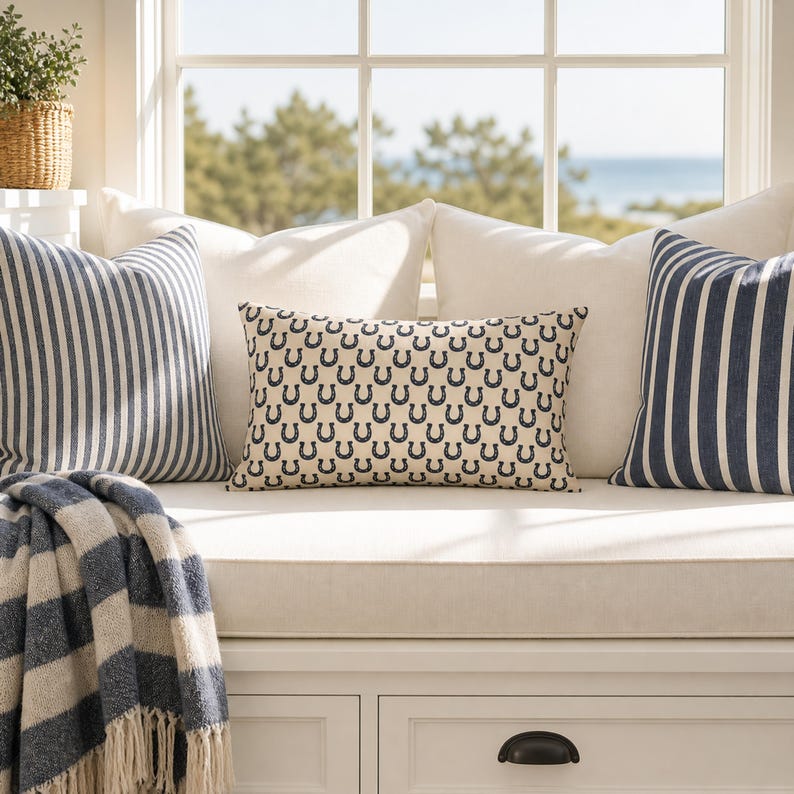 Coastal preppy window seat with horseshoe lumbar pillow, navy striped cushions, equestrian farmhouse decor styling