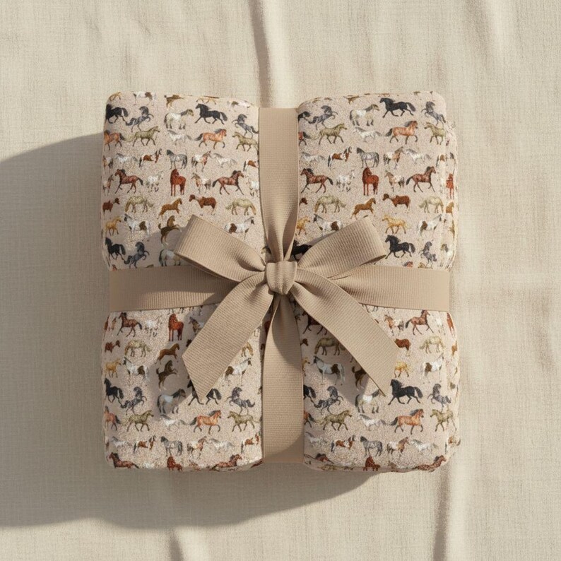 Folded beige horse plush blanket tied with ribbon, velveteen throw blanket gift for horse lovers, equestrian gift idea, western decor blanket, soft plush cozy throw, horse girl birthday gift, Christmas horse gift, farmhouse neutral blanket, horse themed home decor, country style throw blanket, luxury soft bedding accessory, aesthetic horse pattern, cozy comfort gift, western home accent, horse lover present
