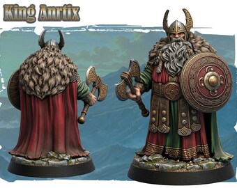 Puede incluir: Una figura en miniatura del Rey Anrtix, un guerrero barbudo con casco de cuernos, capa de piel y túnicas rojas y verdes. La figura sostiene un escudo redondo y un hacha de guerra, mostrada de frente y de espaldas sobre una base de piedra.