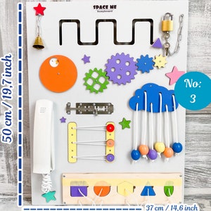 May include: A white busyboard with various interactive elements, including gears, a cloud with hanging beads, and a telephone. The board is 19.7 inches tall and 14.6 inches wide, with the text "SPACE ME busyboard" and "No: 3".
