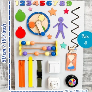 May include: A white wooden busy board with various interactive elements. Includes colorful numbers, shapes, a clock, abacus, zippers, buckles, switches, and an hourglass. The board measures 19.7 inches tall and 14.6 inches wide.