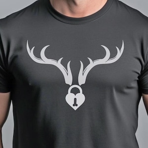 May include: Dark gray t-shirt featuring a white graphic of deer antlers above a heart-shaped lock. The antlers are stylized and symmetrical, with curved tips. The lock has a keyhole at the bottom.