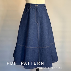 May include: A dark blue denim skirt featuring a high-waisted design with a single button closure, a front zipper, two side pockets, and a horizontal seam detail above the flared hem. The text PDF PATTERN + VIDEO TUTORIAL is visible.