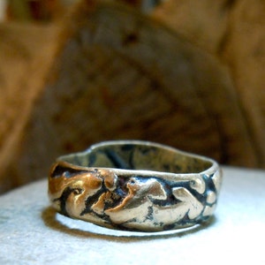 May include: A gold-toned ring with a textured, ornate design. The ring is made of metal and has a rounded shape.