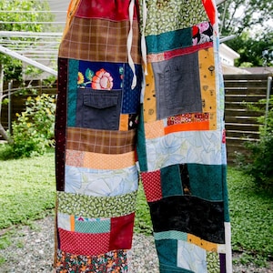 May include: Pants constructed from a variety of colorful fabric patches featuring diverse patterns including floral, plaid, and polka dot designs. The garment includes an elastic waistband with a white drawstring and two dark gray pockets.
