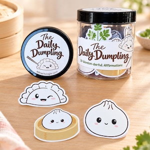 以下が含まれることがあります： The Daily Dumpling 30 Wonton-derful Affirmationsとラベルが貼られた黒い蓋付きの透明なプラスチックジャー。中には餃子をテーマにしたステッカーが入っています。手前には、可愛らしい笑顔の餃子のイラストが描かれた3枚のダイカットステッカーが置かれています。