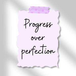 Może przedstawiać: Jasnofioletowa, podarta kartka papieru z napisem "Progress over perfection" napisanym czarnym pismem. Notatka jest przymocowana kawałkiem jasnofioletowej taśmy z r&oacute;żowymi kropkami.