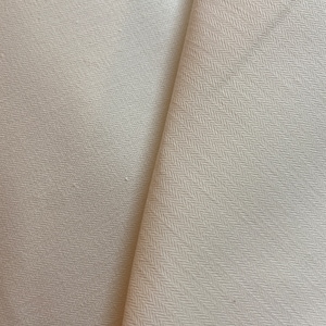 Puede incluir: Primer plano de tela blanquecina con un sutil patrón de tejido en espiga. La tela está doblada, revelando la textura y la dirección del tejido. El material parece ser de peso medio, adecuado para varios proyectos de costura.