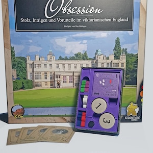 Op de afbeelding: Bordspelbox "Obsession" met Duitse tekst. De doos toont een statig herenhuis. Binnenin bevat een paars dienblad spelstukken en kaarten. Het spel is van Strohmann Games.
