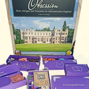 Pode incluir: Jogo de tabuleiro "Obsession" com texto em alemão, com tema da Inglaterra vitoriana. A caixa mostra uma ilustração de uma casa senhorial. Caixas roxas com componentes do jogo estão dispostas ao redor da caixa principal.