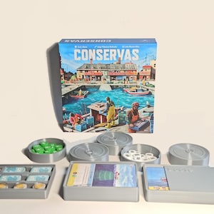 Könnte beinhalten: Ein Brettspiel namens Conservas mit einer Schachtel, die einen Hafen zeigt, begleitet von grauen Kunststoff-Aufbewahrungsschalen mit grünen Spielsteinen, weißen runden Markern und rechteckigen Spielkarten mit blau-weißen Motiven.