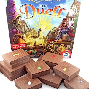 May include: A board game box titled Das Duell featuring fantasy characters and potion bottles, accompanied by several brown plastic storage containers with embossed potion-themed icons including leaves, eyes, and webs on their lids.
