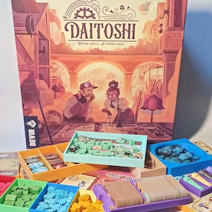 May include: A board game called "Daitoshi" by Dani Garcia and Marina Vidal. The game box features an illustration of a steampunk city with two characters working on a project. The game includes a variety of colorful components, including wooden pieces, tiles, and cards.