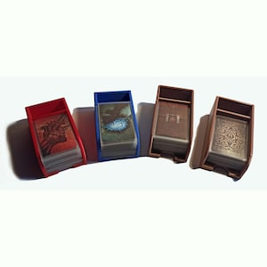 Könnte beinhalten: Vier offene Kartenhalter aus rotem, blauem, braunem und beigem Kunststoff, die jeweils ein Kartenspiel enthalten. Der rote Halter zeigt ein Herzmotiv, der blaue eine leuchtende blaue Kugel, der braune eine Schnalle und der beige ein verziertes Schlüsselloch.