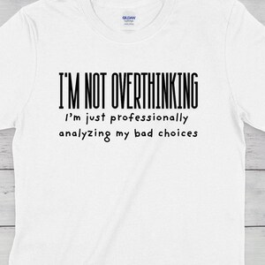 Puede incluir: Camiseta blanca con texto negro que dice "No estoy pensando demasiado, solo estoy analizando profesionalmente mis malas decisiones."