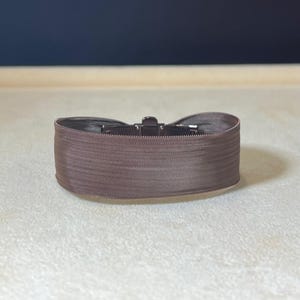 May include: A brown elastic belt with a metal buckle.