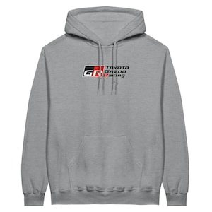 Puede incluir: Una sudadera con capucha gris con un logotipo rojo y negro que dice "TOYOTA GAZOO Racing" y "GR" en un cuadro.