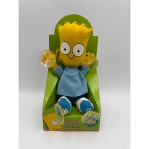 May include: A Bart Simpson stick-on doll in a green cardboard display. The doll has a yellow head, blue shirt, and blue shorts. The doll has two clear suction cups attached to its arms. The packaging has the words "BART SIMPSON" and "STICK-ON".