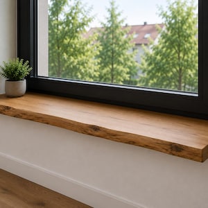 Può includere: Un davanzale in legno naturale con bordo grezzo e finitura a venature marrone caldo installato sotto un telaio di finestra nero. Una piccola pianta verde in un vaso di cemento grigio è posizionata sul lato sinistro della mensola.