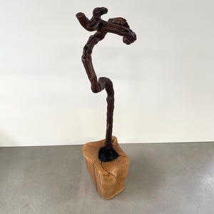May include: A wooden sculpture of a tree with a twisted trunk and branches. The sculpture is mounted on a wooden base.