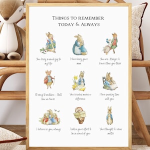 以下が含まれることがあります： 「THINGS TO REMEMBER TODAY & ALWAYS」のテキストとウサギのイラストが描かれた額入りのプリント。明るい木製のフレームで、ぬいぐるみとクッションが付いた木製の椅子に飾られています。