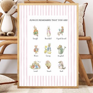 Puede incluir: Un estampado enmarcado con un marco de madera clara que presenta ilustraciones de acuarela de conejos y otros animales. El texto "ALWAYS REMEMBER THAT YOU ARE" está en la parte superior, con palabras como "valiente", "cariñoso" y "amable" debajo.