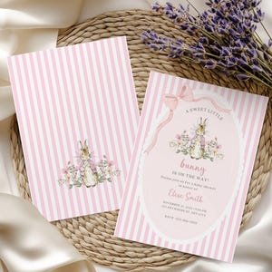 Könnte beinhalten: Zwei rechteckige Einladungskarten für eine Babyparty mit einem vertikalen Streifenmuster in Rosa und Weiß. Die Karten zeigen eine Aquarellillustration eines Hasen, umgeben von Blumen, mit dem Text A SWEET LITTLE bunny IS ON THE WAY!